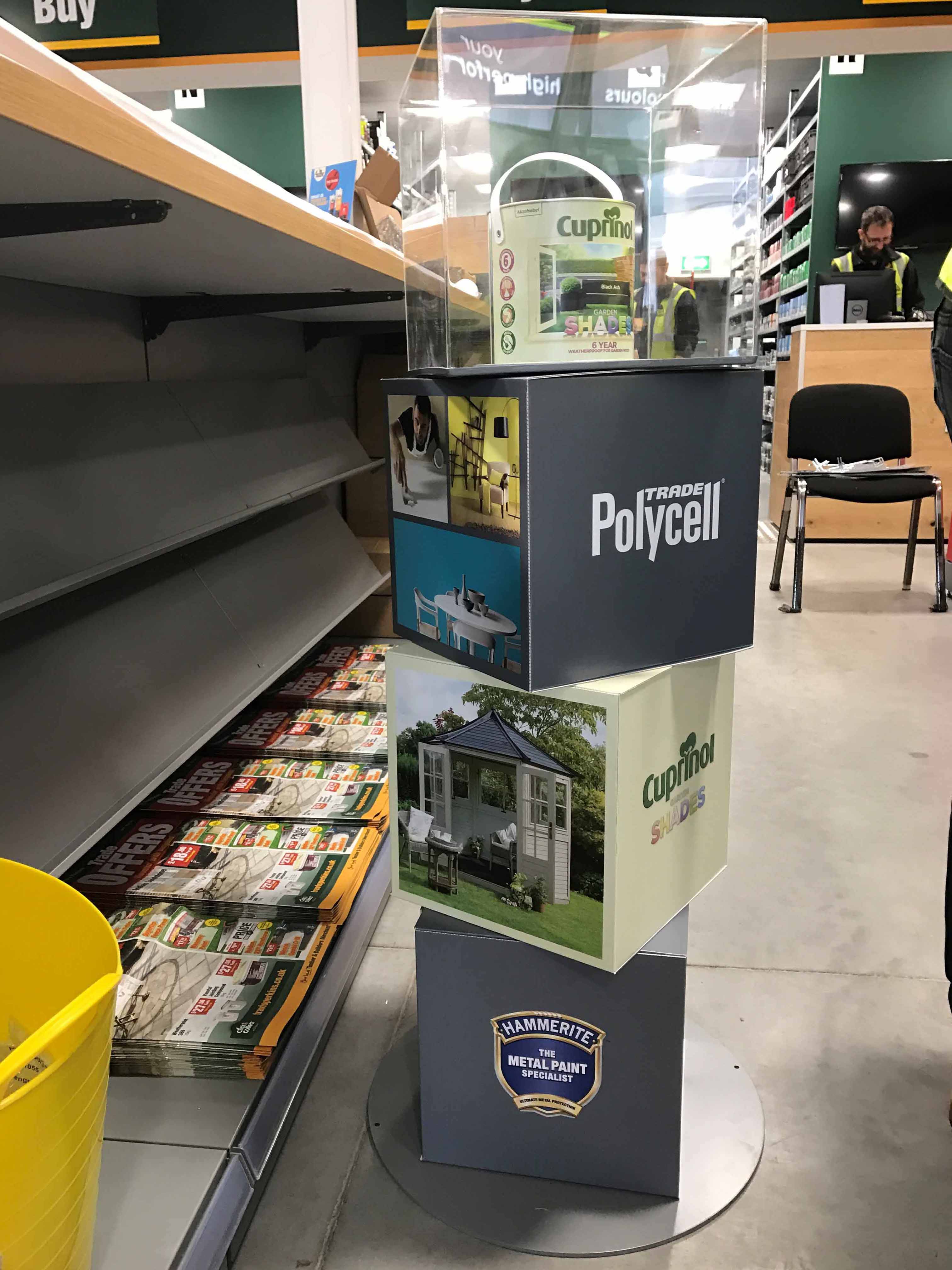 Gardena branded semi-permanent POS display stand holding spades, forks and rakes with teal handles at a trade exhibition